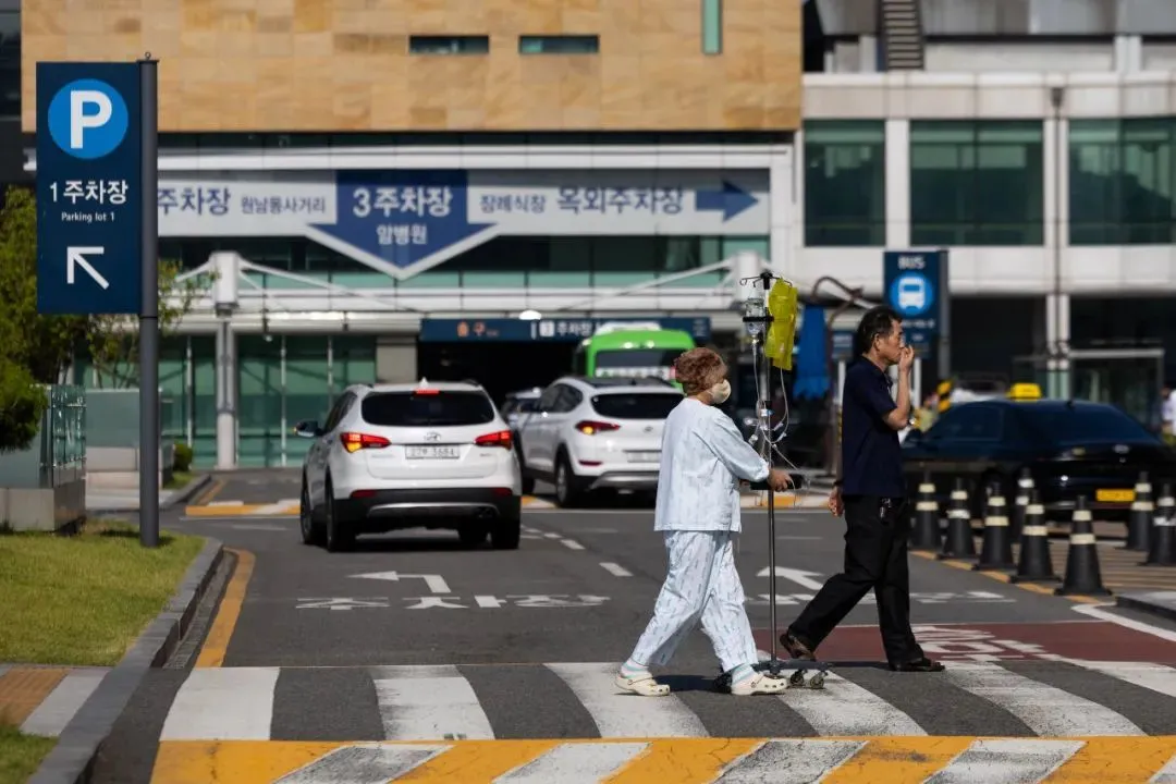 ▲2024年6月,韩国医生游说团体呼吁进行全国性一日罢工,首尔国立大学医院的一名病人自行推着输液架走在路上。