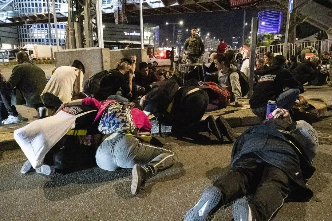 2023年，12月2日，在以色列城市特拉维夫，防空警报响起时，身处室外的人们降低身位避难/新华社记者 陈君清 摄