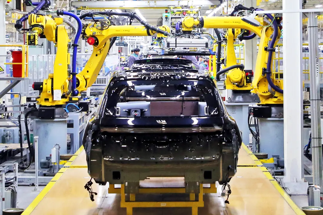 理想汽车基地的生产车间，机器臂在组装新能源汽车。