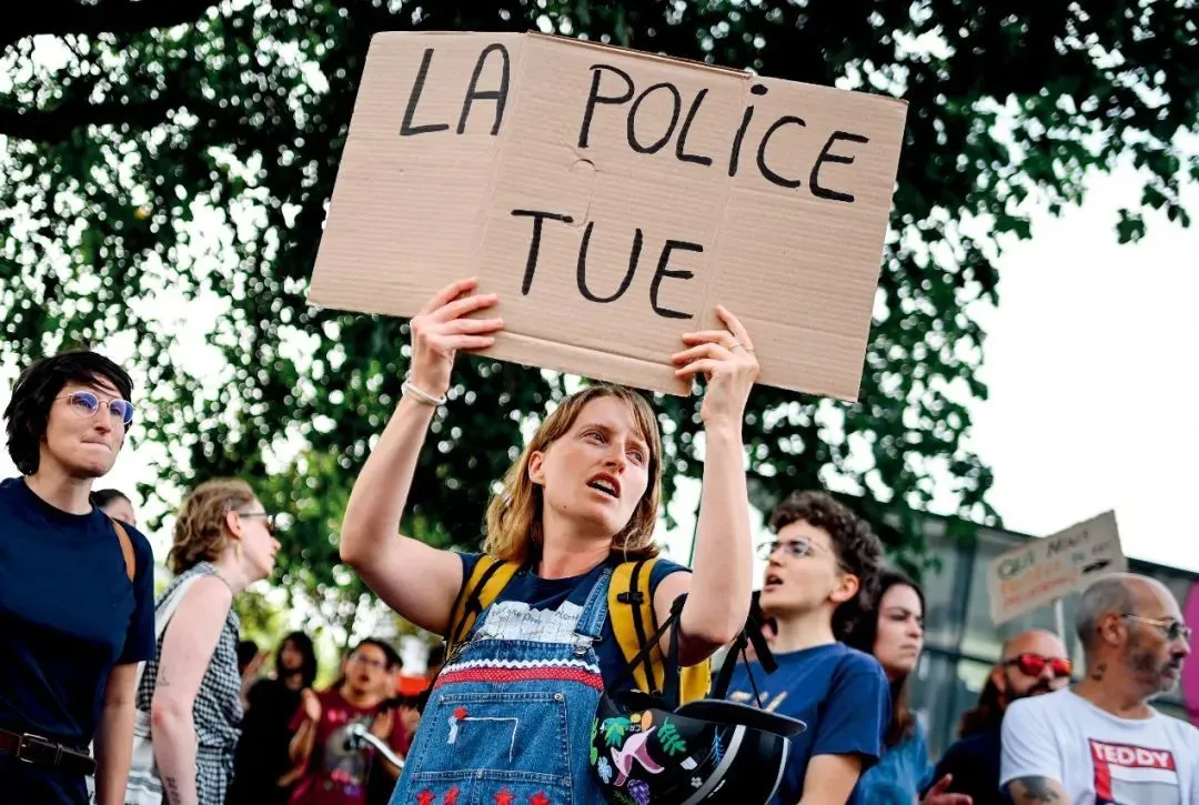 6月28日，法国南特，一名抗议者举着写有“警察杀人”的标语。图/视觉中国