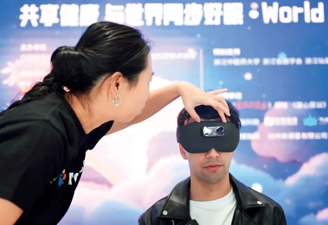 2025年3月21日，在浙江杭州的世界睡眠日“每天早睡一小时”公益活动期间，参与者体验安睡仪。该仪器在采集脑电波后，通过人工智能算法判断神经状态，进而以声光电干预来帮助睡眠。图/中新