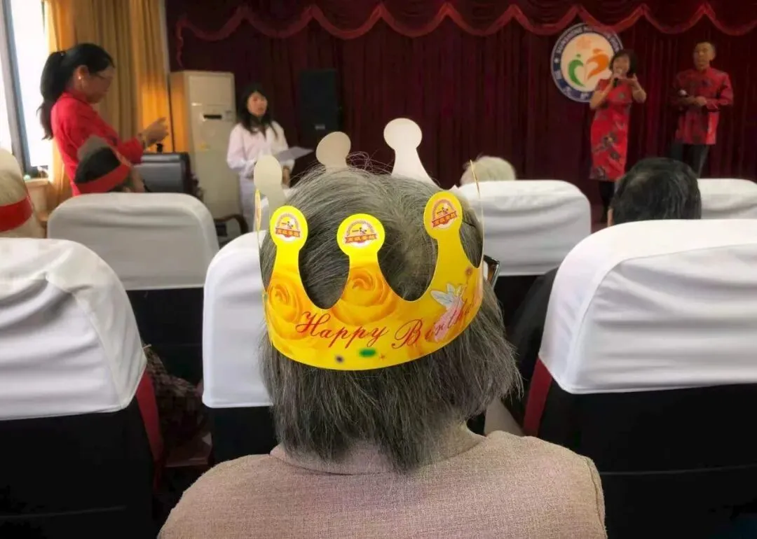 养老院里重阳节慰问演出，戴着纸王冠的是当月生日的寿星 ｜ 受访者供图