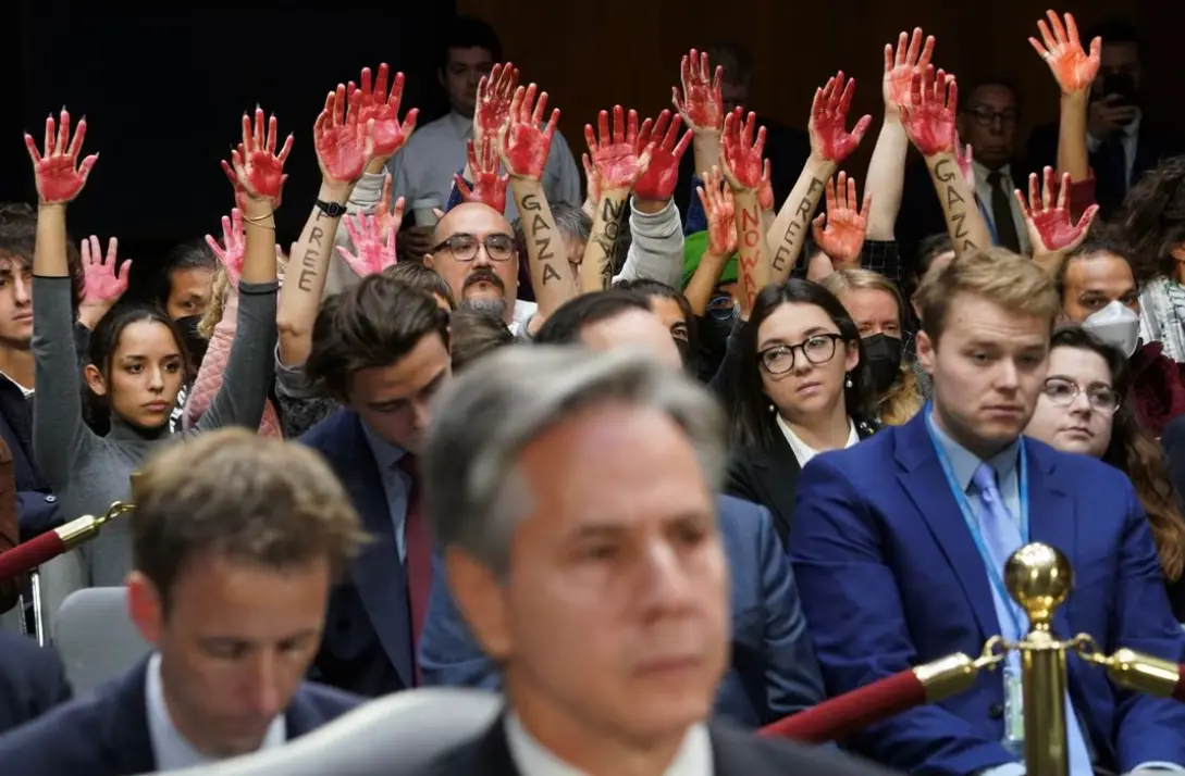 10月31日在参议院拨款委员会听证会上，反战抗议者在布林肯身后举起“血淋淋”的双手。图自路透社