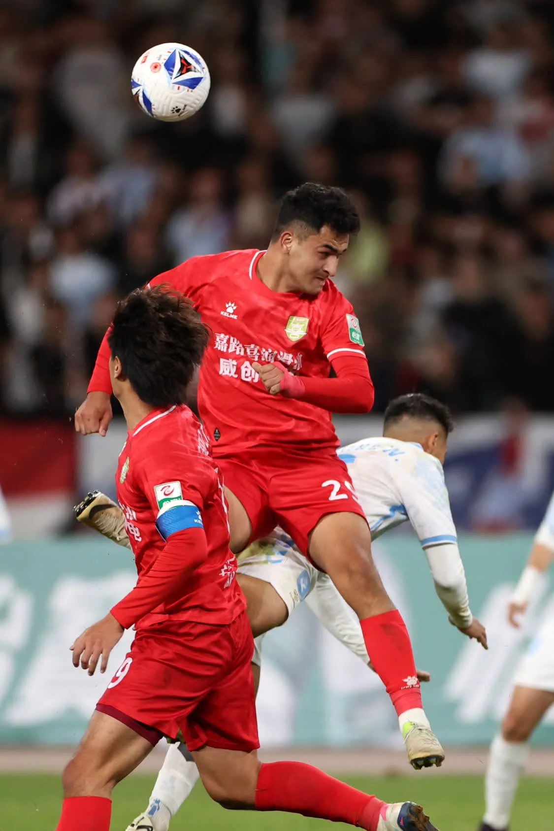 4月5日，长春喜都队球员努尔亚森&middot;买买提（中）在比赛中争抢头球。新华社记者　陈斌　摄