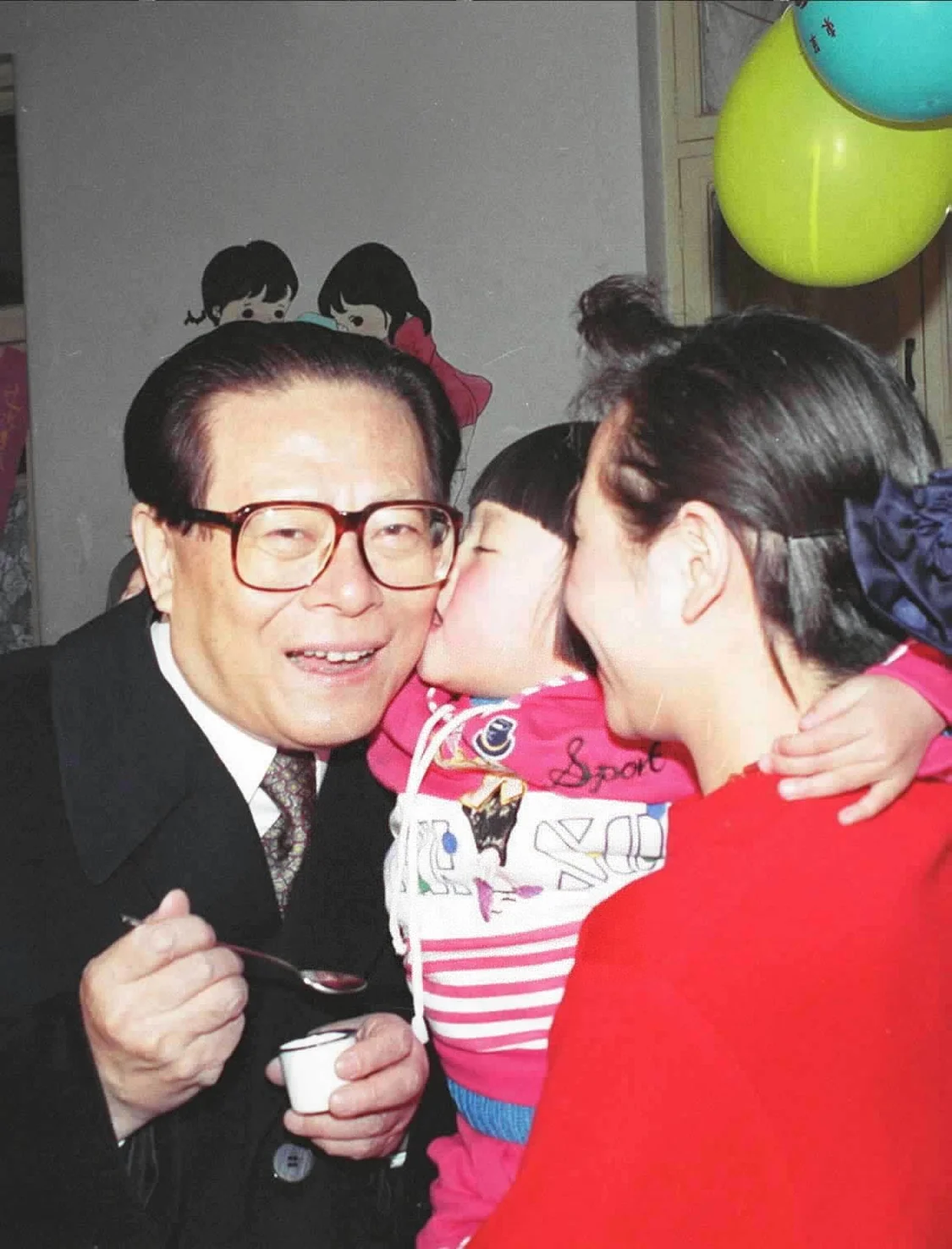 1993年12月5日，江泽民同志在北京为一位幼儿园儿童喂服脊髓灰质炎疫苗后，小朋友亲吻江爷爷。 新华社发