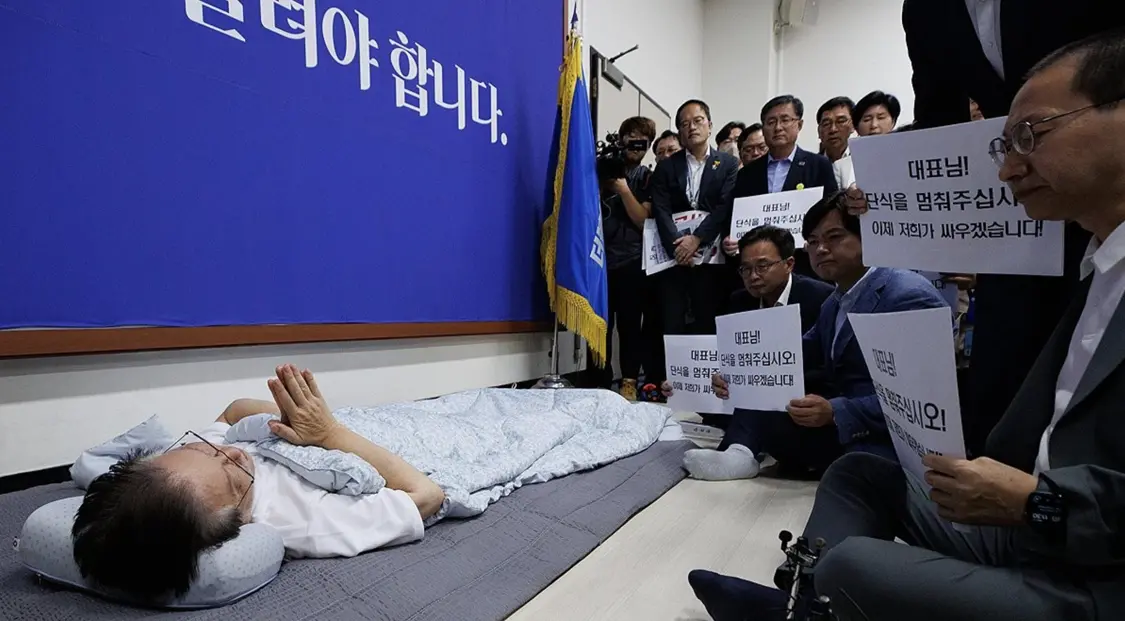 9月15日，无力坐起的李在明双手合十，向呼吁其停止绝食的人问好。（图源：社交媒体）