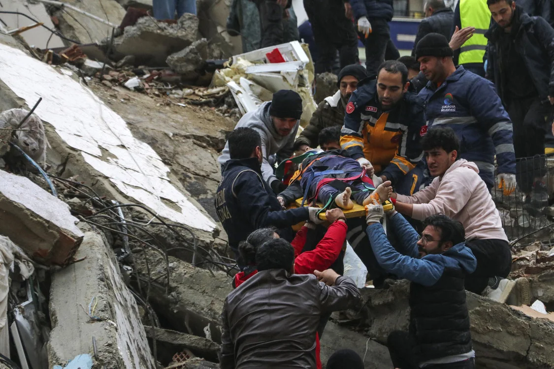 当地时间2月6日，土耳其阿达纳，救援队齐心协力传递担架上的幸存者。