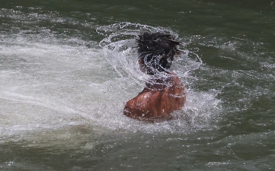 当地时间2023年6月16日，美国得克萨斯州，一名男子泡在公园河水中降温。