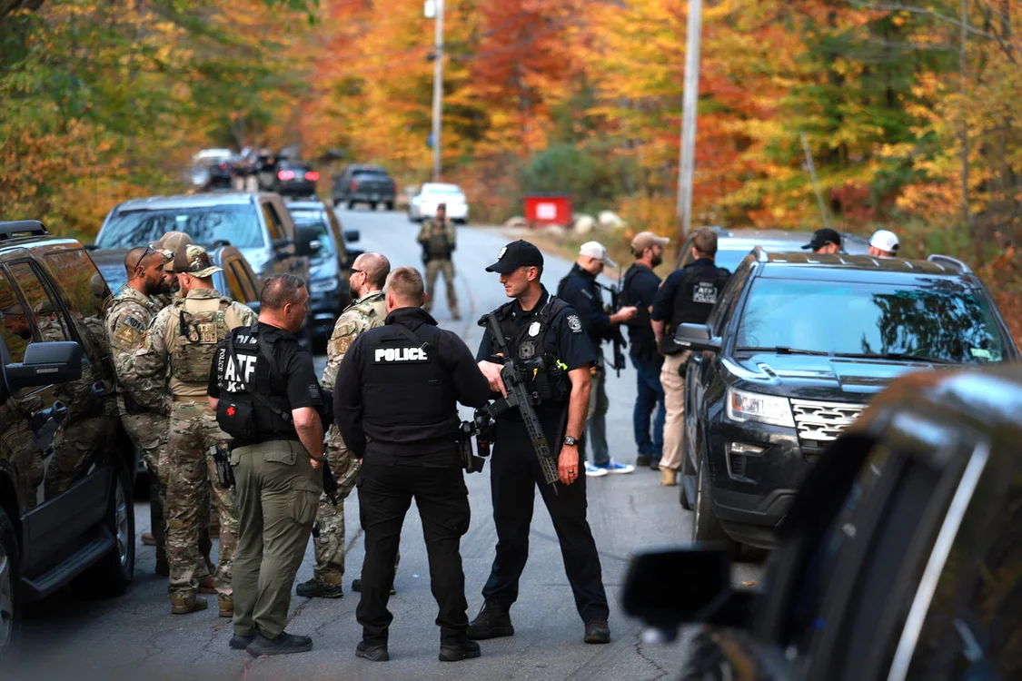 :当地时间10月26日，缅因州鲍登镇，执法人员聚集在通往嫌疑人家的道路上。