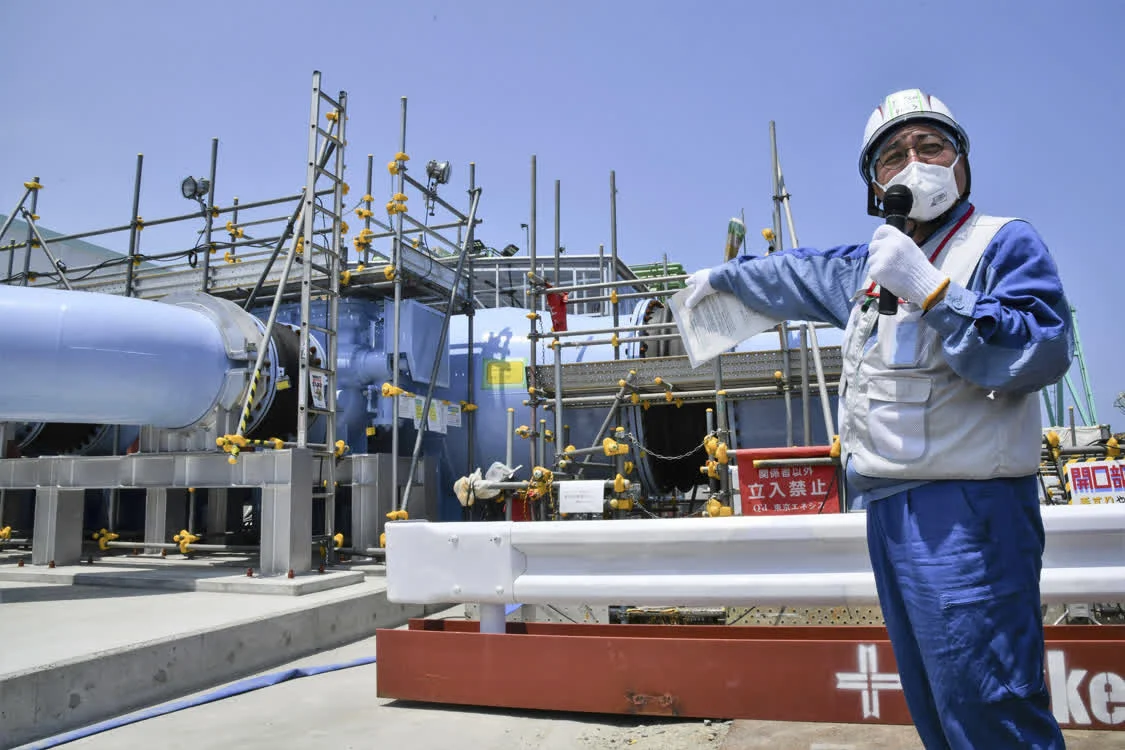 日本东京电力公司的一名员工在福岛第一核电站向媒体解释用于排放核污水的设施（美联社资料图片）