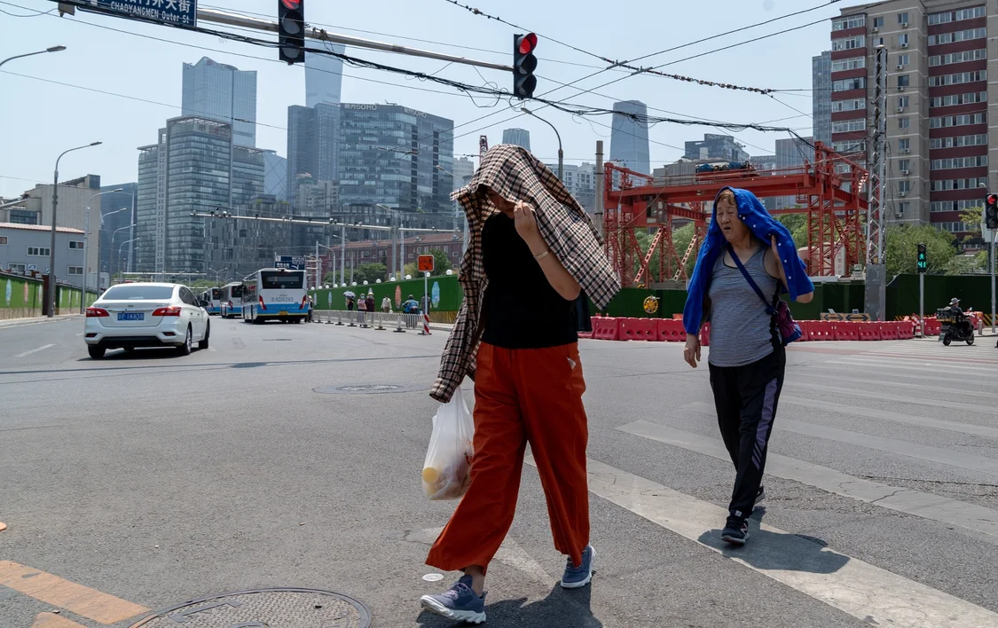 资料图：6月24日，北京市民在热浪中用衣服遮阳（图片来源：CFP）