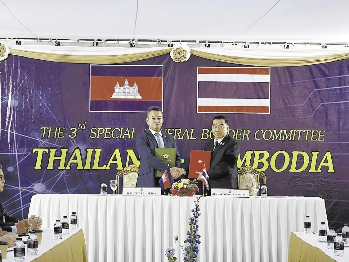 12月27日，柬埔寨副首相兼国防大臣迪西哈（左）与泰国国防部长纳塔蓬在边界总委员会第三次会议上交换停火协议文件。（视觉中国）