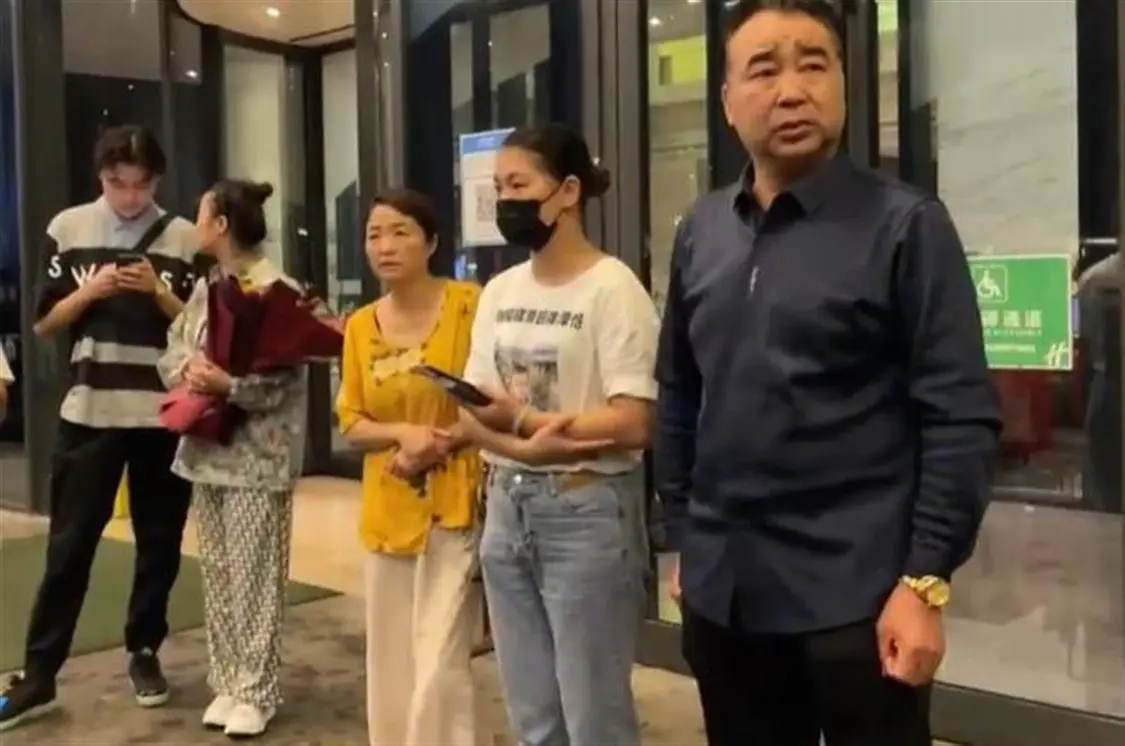 梅贤华（右一）与家人在酒店门口等待儿子梅志强的到来（图源：直播截图）.jpg