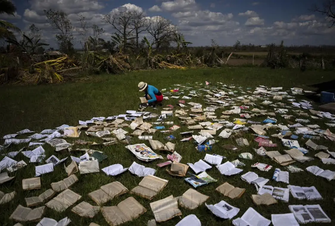 古巴，一位教师正在晾晒被暴雨打湿的书本。图源：AP
