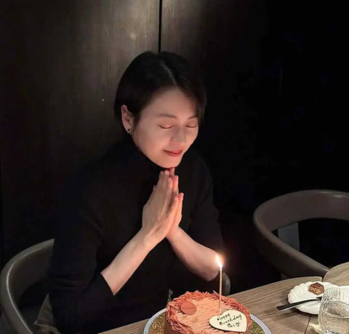 梁咏琪双手合十，对着蛋糕闭眼许愿，状态超好。