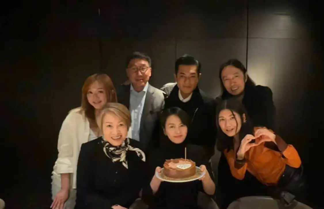 搜狐娱乐讯 25日，49岁梁咏琪的一组庆生照曝光，古天乐等好友现身为她庆祝生日。梁咏琪穿着黑色高领毛衣，手捧蛋糕与好友们同框合影，心情大好。