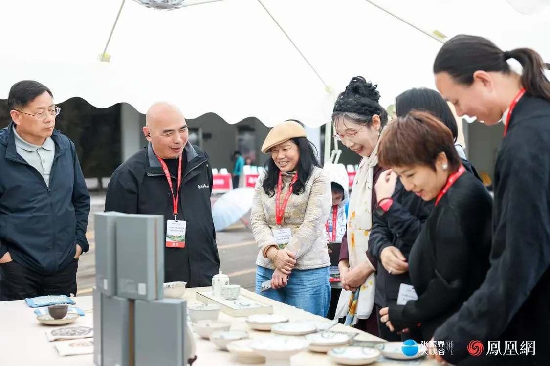 （嘉宾们欣赏省级非遗传承人彭望球的长沙铜官窑作品。）