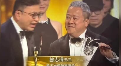 曾志伟云南吃饭，穿宽松卫衣配阔腿裤很休闲，美女叼杯敬酒一脸满足