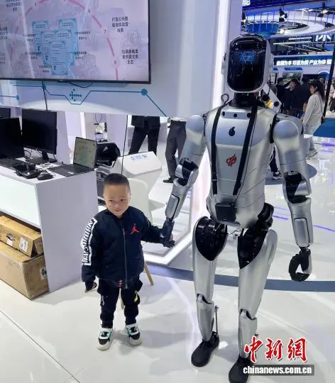 10月19日，中国数博会上，小朋友同讲解具身智能机器人牵手。王少波 摄