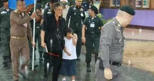 ·诗琳通公主搂着女孩在雨中走向教学楼。