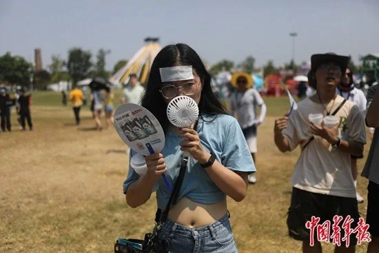 8月21日，四川省成都市一场户外音乐节上，一个女孩手持小风扇，额头上贴着清凉贴。中青报·中青网记者 孔斯琪/摄