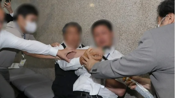 图为15日，韩国国会警备队注意到该男子试图写血书自残行为，立即采取行动制止。图源：韩媒