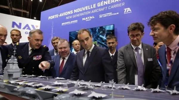 展会首日，法国军方官员在展台前仔细欣赏未来航母的模型。（法新社）