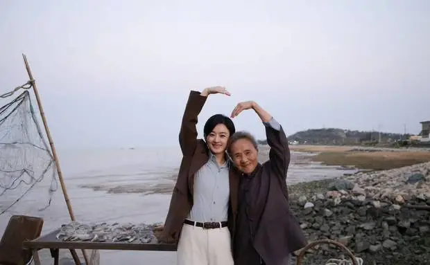 二人抬手比心，笑容灿烂。