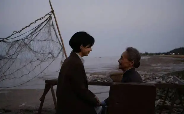 二人相视而笑，祖孙情谊在海边流淌。