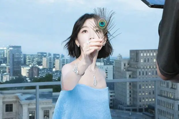 周冬雨手持孔雀羽抬眼，清冷温柔。