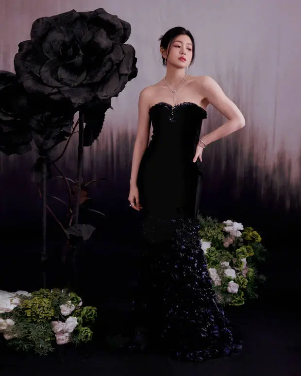 陈妍希单手叉腰立于巨型黑玫瑰旁，黑色抹胸裙裙摆轻垂，项链点缀添精致。