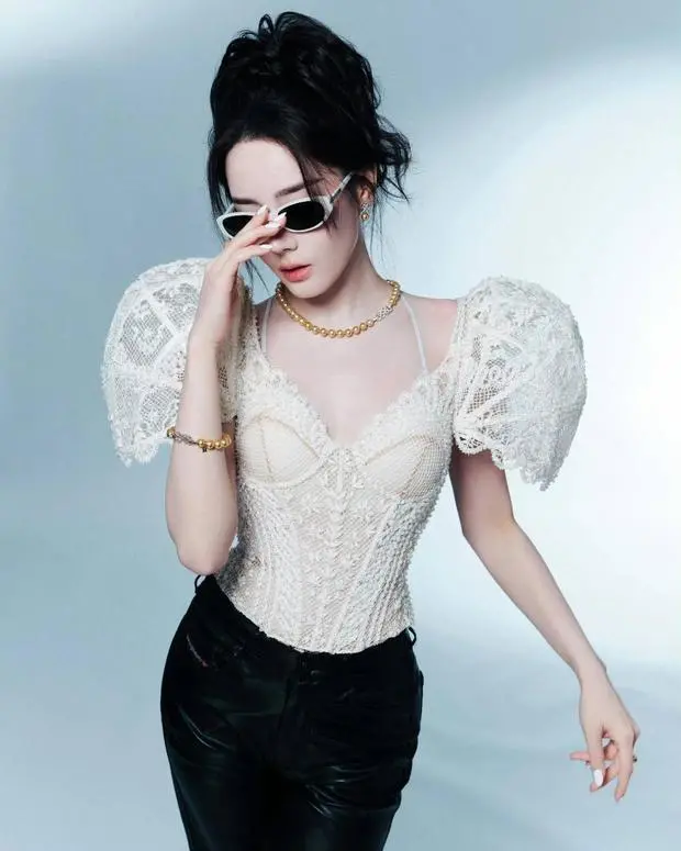迪丽热巴手轻扶墨镜，珍珠项链与蕾丝衫呼应，，尽显摩登女郎风范。