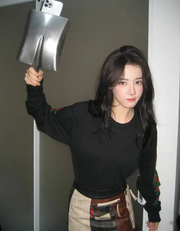 迪丽热巴用铁锨手机壳摆拍,仿佛下一秒手中的铁锨就能用作武器。