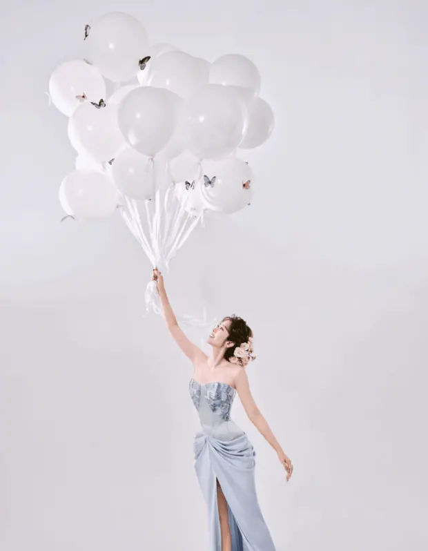 唐艺昕手持白色气球，背景的简约色调衬出礼裙的清新。