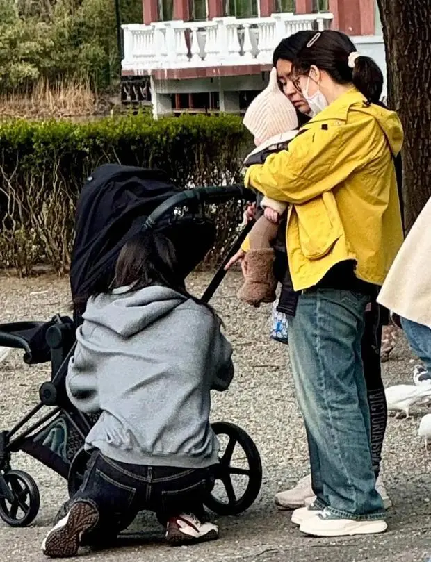 何穗蹲在婴儿车旁。