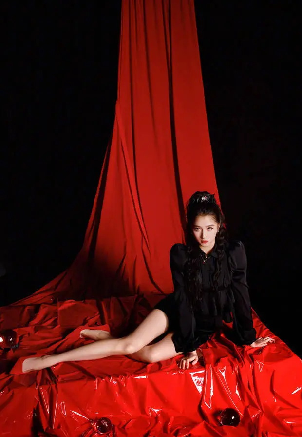 关晓彤坐在红色背景布上,眼神清冷。