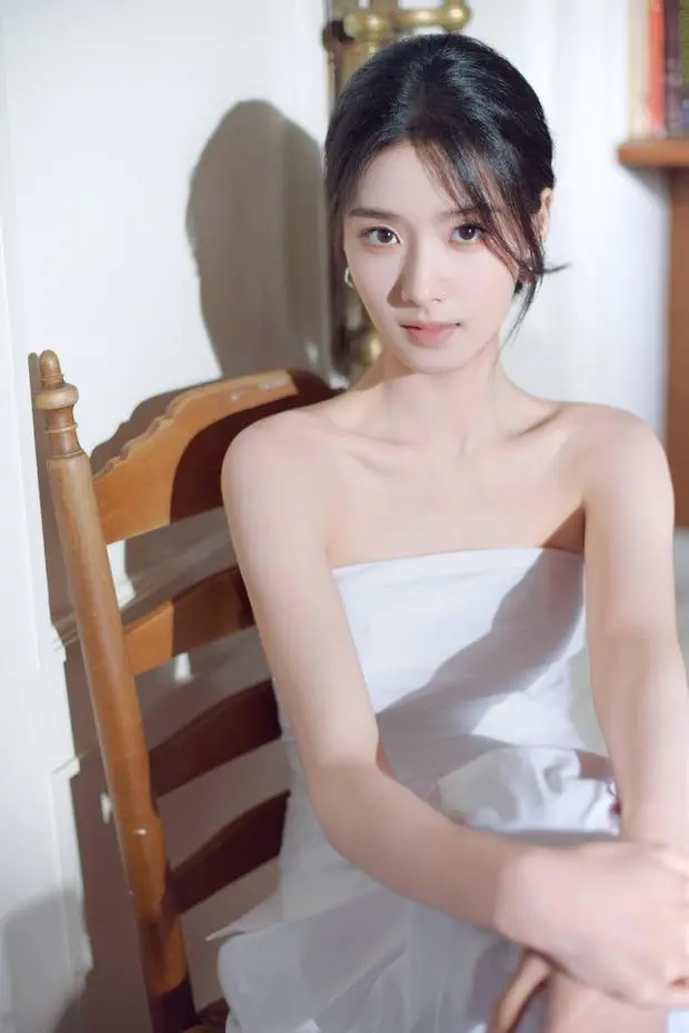 卢昱晓坐木椅上，直视镜头。