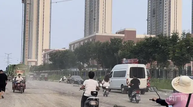 新郑市祥和路第一小学门口的主路上，车辆经过时尘土飞扬（央广网 见习记者张丽娜 摄）