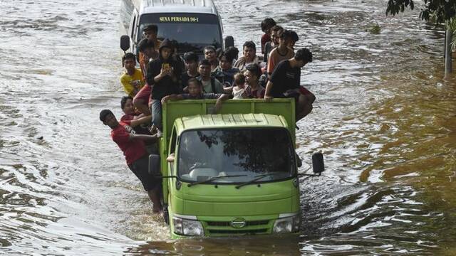 印尼爆发洪灾 民众在积水中艰难前行