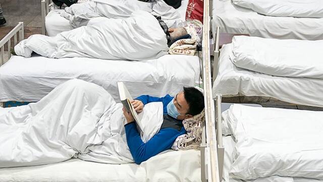 武汉“方舱医院”启用 新冠肺炎轻症患者在床上看书刷手机