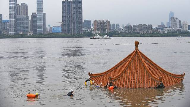 武汉：洪峰过境 市民在江畔凉亭附近游泳