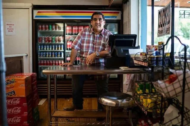 老板杰拉尔多·莫拉莱斯站在玉米饼工厂的柜台后面。
