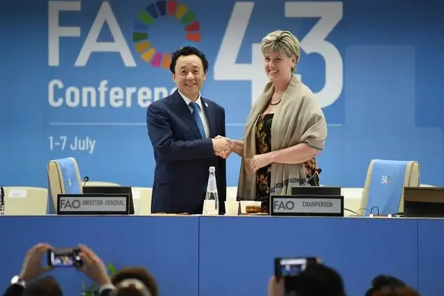 2023年7月2日，意大利罗马的联合国粮食及农业组织总部，屈冬玉（左）胜选连任后与粮农组织大会第43届会议主席玛丽-克洛德·比博握手。图：新华社记者 金马梦妮 摄