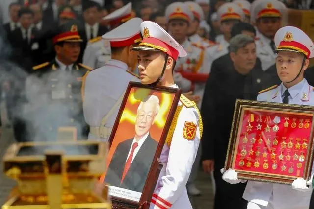 7月26日，在越南首都河内，一名士兵在葬礼上手持阮富仲的肖像 图：新华社/美联