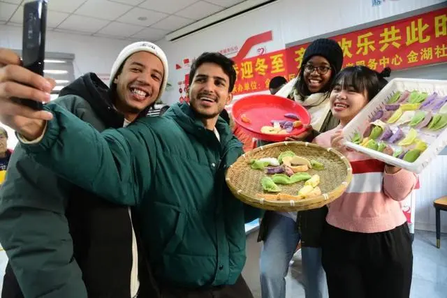在江苏省镇江市金湖社区,江苏大学的外国留学生与包好的饺子自拍“合影”。石玉成 摄