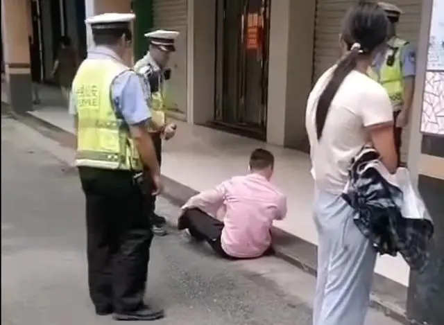 视频显示疑身着交警制服的工作人员向坐在地上的男子使用喷雾