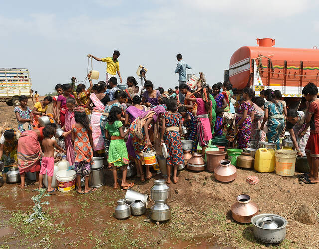 很多人排队在水井旁取水.