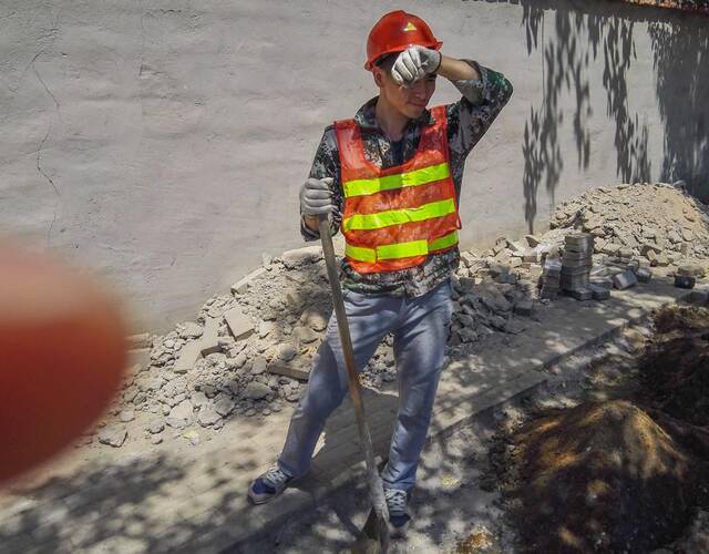 蒋栋平干活累了,擦擦汗休息一会,然后再接着干.