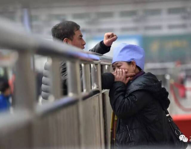 合肥火车站广场入口处,妻子一只手提着行李,一只手