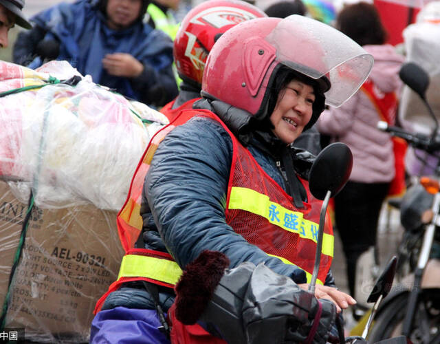 图为张女士搭着丈夫,从广东中山市冒雨赶回广西平南县老家.